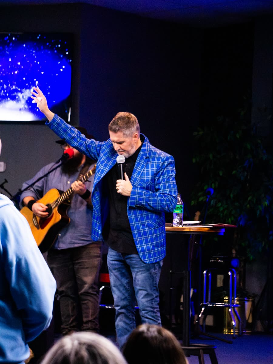 A minister with one arm raised, leading in prayer