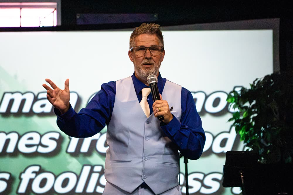 A speaker in a vest and tie teaching with a microphone